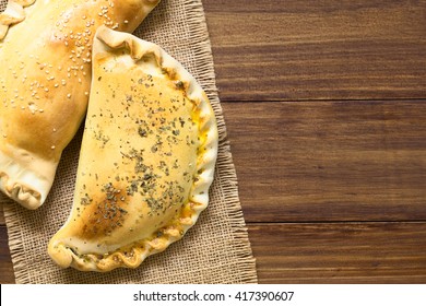 Chilean Empanadas, Baked Stuffed Pastry Stuffed With Cheese And Ham, Photographed Overhead On Dark Wood With Natural Light