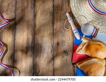 Chilean independence day concept. fiestas patrias. Tipical baked empanadas, wine or chicha, fat and play emboque. Decoration for 18 september party day, wooden background, top view. - Shutterstock ID 2194479705