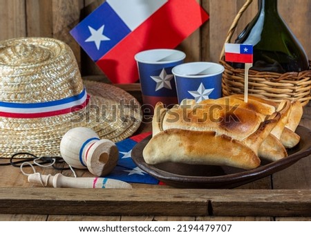 Chilean independence day concept. fiestas patrias. Tipical baked empanadas de pino, wine or chicha, hat and play emboque. Dish and drink on 18 September party, wooden background.