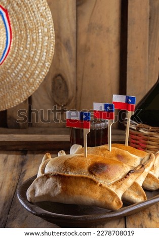 Chilean independence day concept. fiestas patrias. Tipical baked empanadas de pino, wine or chicha, hat and play emboque. Dish and drink on 18 September party, wooden background