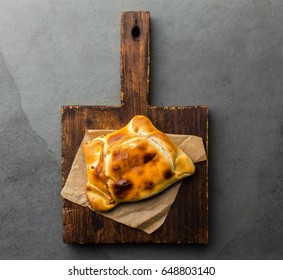 Chilean Typical Food. Empanada De Pino Chilena Served On Wooden Board. Slate Gray Background, Top View