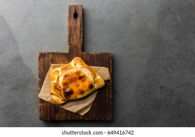 Chilean Typical Food. Empanada De Pino Chilena Served On Wooden Board. Slate Gray Background, Top View, Copy Space