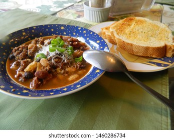 chili with beans in a bowl with garlic toast on the side