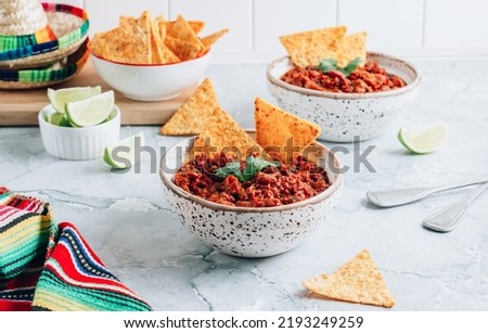 Chili con carne in bowls with tortilla chips on a gray marble background. Traditional dish of mexican cuisine. Selective focus