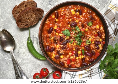 Chili con carne in a clay bowl on a concrete or stone rustic background- traditional dish of mexican cuisine.Top view.