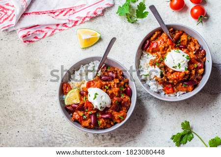 Chili con carne with rice in a gray bowl. Beef stew with beans in tomato sauce with sour cream and rice. Traditional Mexican food concept.