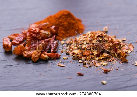Chili peppers on rustic background (dreid, powder, chopped)