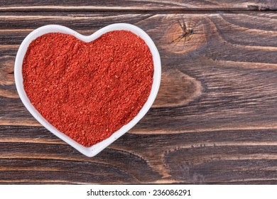 Chili Powder In A Bowl In The Form Of Heart On A Wooden Background