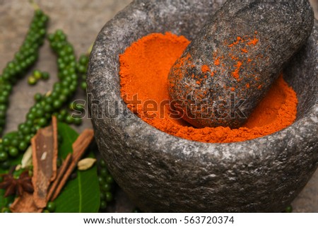 Chili powder in a mortar Kerala South India. Women hand in traditional Indian kitchen using vintage grinder for powdering spices which is used widely in curry to make it red hot and spicy.