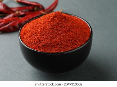 Chili powder is a seasoning blend of ground dried chiles in a black bowl with dried red chiles on a gray background. - Powered by Shutterstock