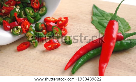 Chili red and green sliced in white ceramic bowl on wooden cutting board, Red hot chili peppers is an herb with medicinal properties, Spicy seasoning ingredients (Macro shot).