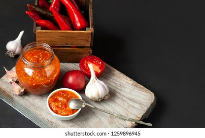 Chili sauce, tomatoes and hot red pepper on a wooden background, rustic style.