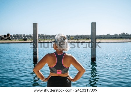 Chill aged woman in sports clothes facing an urban lake