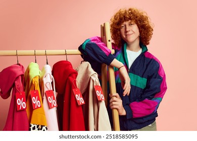 Chill and ready for sales, stylish shopper leans against rack of vibrant, discount-tagged clothes, eyeing best deals against pink background. Concept of Black Friday, Cyber Monday, fashion, Flash Sale - Powered by Shutterstock