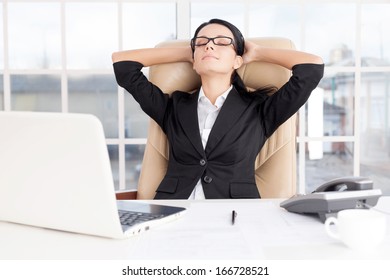 Chill Time. Cheerful Young Business Woman Holding Head In Hands And Keeping Eyes Closed While Sitting At Her Working Place