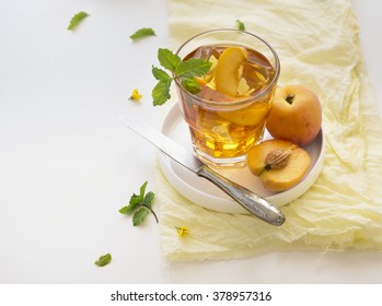 Chilled peach tea in glass with fresh cut peaches on white background. Text space image.