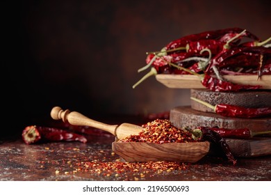 Chilli flakes and dried chili peppers on a brown table. - Shutterstock ID 2196500693
