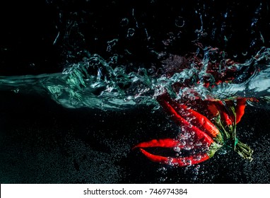 Chilli. Red pepper in water with splash on a black background
