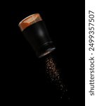 Chilli seasoning powder flavor falling from shaker bottle, red chilli and seasoning powder splash in mid air. Seasoning powder shaker spice up taste of food over black background isolated