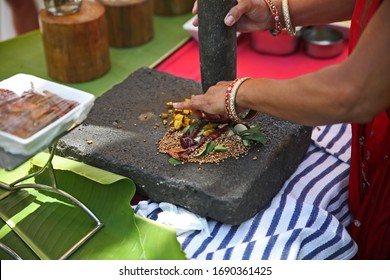 Chilli and spices being crushed on a traditional indian vintage grinding stone / stone mortar. Indian spices for hot and spicy curry / cuisine / dish. - Powered by Shutterstock