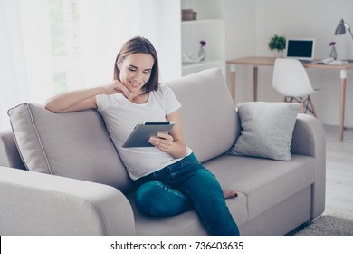 Chilling gorgeous brown haired freelancer on the beige couch at home doing online shopping, so comfortable, in fashioanble white outfit, denim pants, so nice light design interior indoors - Powered by Shutterstock