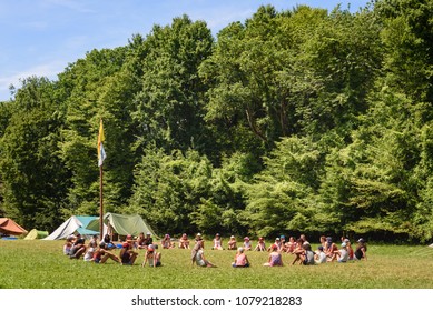 CHIMAY, BELGIUM. JULY 9, 2017. Group Of Scout Teenagers Sitting In Circle On Grass At Campsite With Youth Organisation Summer Camp In Wallonia, Belgium.