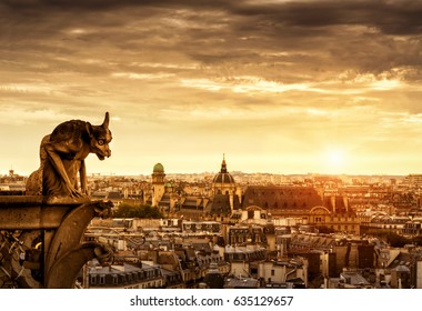 Chimera or gargoyle on the Cathedral of Notre Dame de Paris overlooking Paris at sunset, France. Panorama of Paris with the evil statue in sunlight. Beautiful sunny view of Paris under dramatic sky.