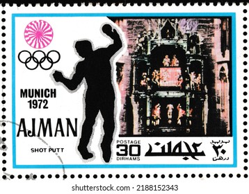 Chimes At The Town Hall, Shot Put - Ajman, Circa 1971: Postage Stamp Of The 1972 Summer Olympics Series, Munich (III).