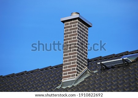 Chimney clad with clinker bricks on a newly covered roof
