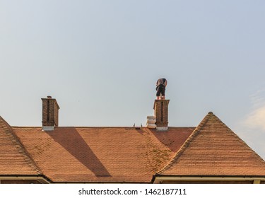 Chimney Liner Installation On A 1930 Built House. A Skilled Installer Can Be Seen Placing The Metal Liner Tube Inside The Chimney Working At A High Level. 