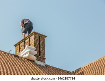 Chimney Liner Installation On A 1930 Built House. A Skilled Installer Can Be Seen Placing The Metal Liner Tube Inside The Chimney Working At A High Level. 