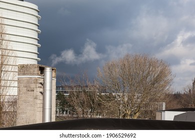 Chimney On The Flat Roof Off A Big Building In The City With A Plume Of Smoke