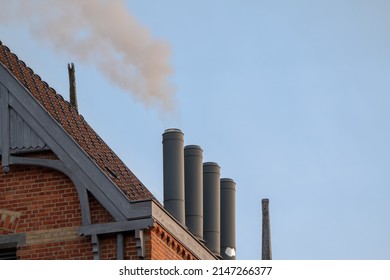 Chimney On The Flat Roof Off A Big Building In The City With A Thick Plume Of Smoke