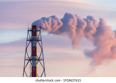 A Chimney Of A Power Plant And Clouds Of Smoke, Illuminated By Red Sunlight At Sunrise. Aerial View Of High Smoke Stack With Smoke Emission. Industrial Zone, Thick Smoke Plume. Industry And Ecology.