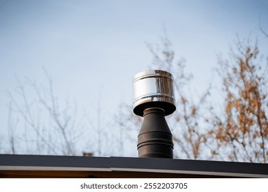 A chimney rising prominently above the top of a roof, beautifully framed by trees in the background, creating a picturesque scene that adds character to the overall architecture of the building - Powered by Shutterstock