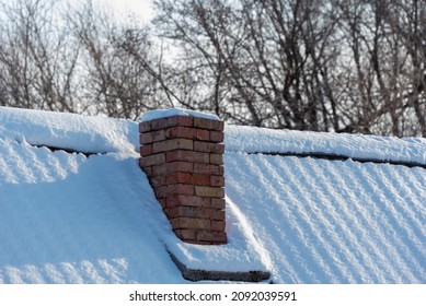 Chimney and snow-covered roof of a house in the village.