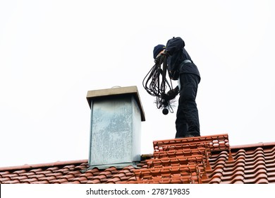 Chimney sweep standing on roof of home working