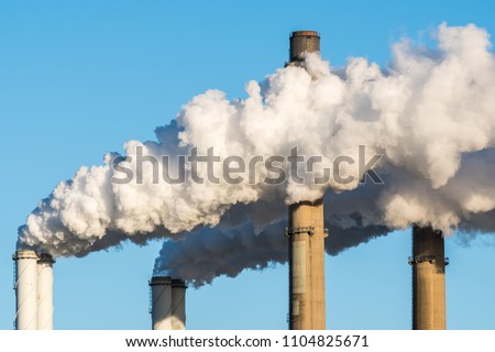 The chimneys of a powerstation with huge smoke stacks and a blue sky as background.