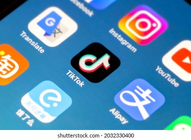 China - 22nd August 2021: Tik Tok Application Icon In Focus On IPhone Smartphone Screen, Other Apps (Alipay, Instagram Etc) Out Of Focus On Blue Gradient Background Wallpaper