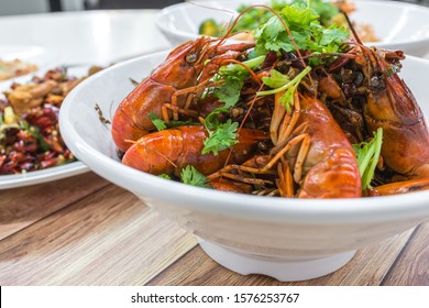 China, Chongqing Sichuan Spicy Dried Chilli Small Lobsters, Among Other Dishes In The Background. Food Photography At Chinese Restaurant.