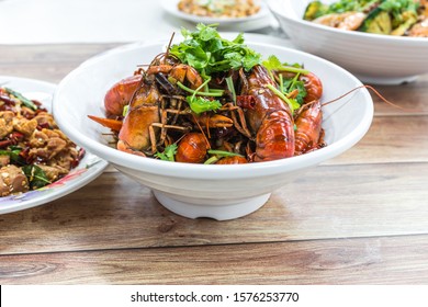 China, Chongqing Sichuan Spicy Dried Chilli Small Lobsters, Among Other Dishes In The Background. Food Photography At Chinese Restaurant.