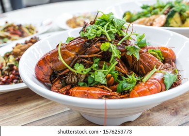 China, Chongqing Sichuan Spicy Dried Chilli Small Lobsters, Among Other Dishes In The Background. Food Photography At Chinese Restaurant.