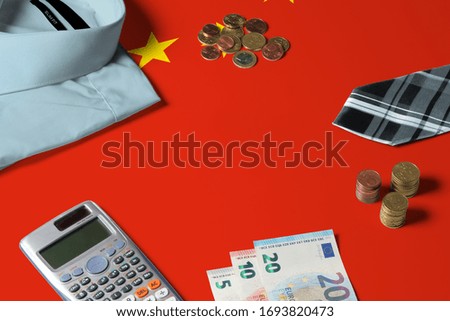 China flag on minimal money concept table. Coins and financial objects on flag surface. National economy theme.