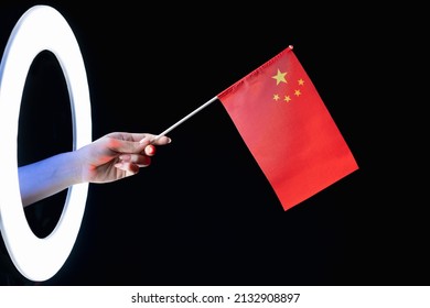 China Flag. Patriotic Symbol. Culture Pride. Female Hand Holding Five-starred Red National Emblem In Glowing LED Light Ring Isolated On Black Background.