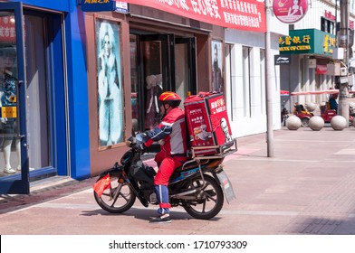 China, Heihe, July 2019: Food Delivery Man On A Scooter. Central Pedestrian Street Of The Chinese City Of Heihe In Summer