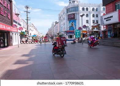 China, Heihe, July 2019: Food Delivery Man On A Scooter. Central Pedestrian Street Of The Chinese City Of Heihe In Summer