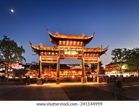 China Nanjing city area around confucius temple with wooden historic gate and background red wall with fire dragons illuminated at sunset