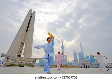 CHINA, SHANGHAI - OCTOBER 1, 2017 : People playing Taiji quan on the Bund in China National Day Celebrations 2017, At Shanghai People's Heroes Monument. Oriental Pearl Tower in the distance.