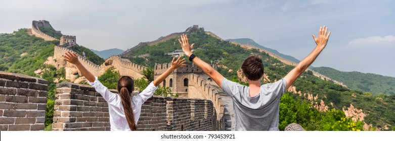China travel people winning of joy in Asia on Great Wall, Beijing, chinese landmark. Young couple tourists with arms up in happiness winners visiting Great Wall panorama landscape crop for background.