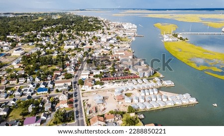 Chincoteague Island, marinas, houses and motels with parking lots. bridge and road along the bay. Drone view.